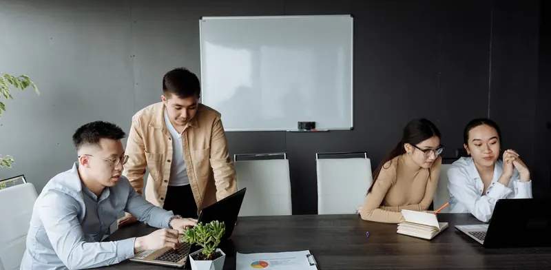 Team working together on laptops around an office meeting table