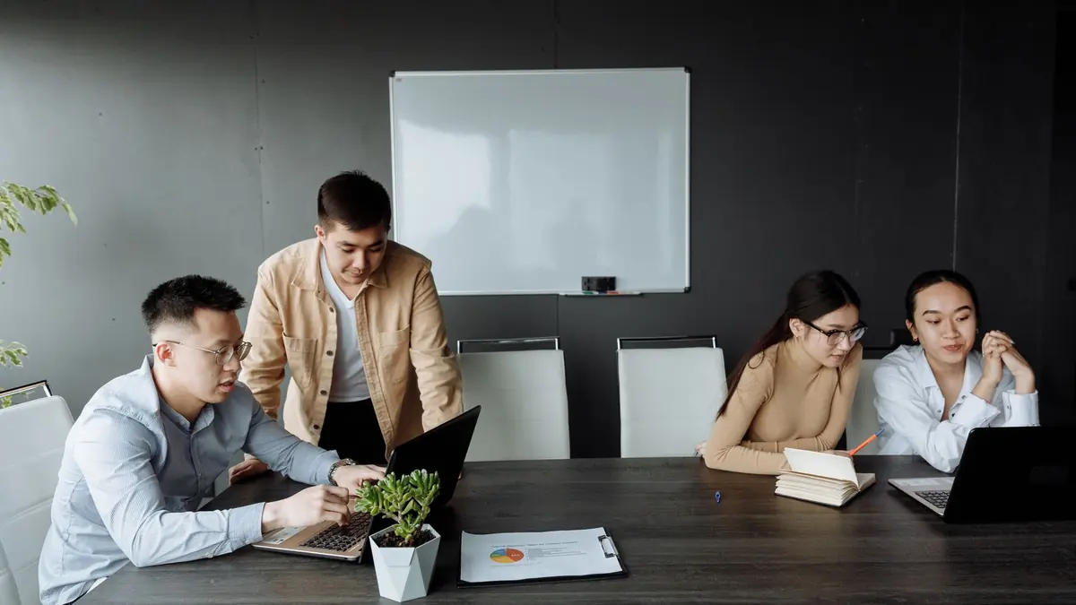 Team working together on laptops around an office meeting table