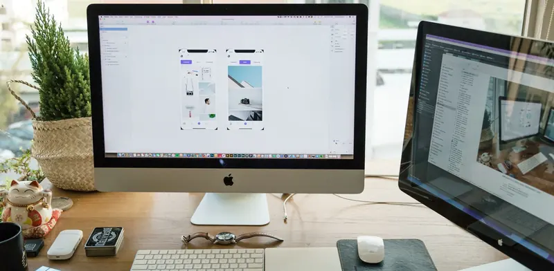 Desktop all-in-one computer with keyboard and mouse set up on a wooden desk by a window