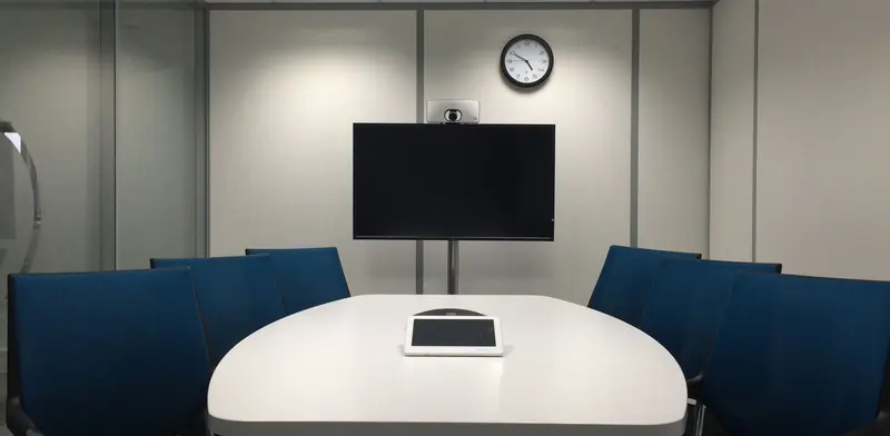 Meeting room with a large screen and video conference camera at the head of the table