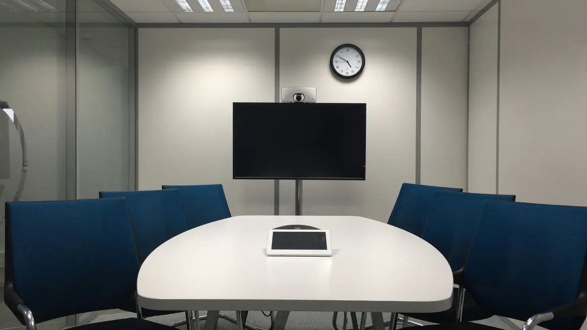 Meeting room with a large screen and video conference camera at the head of the table