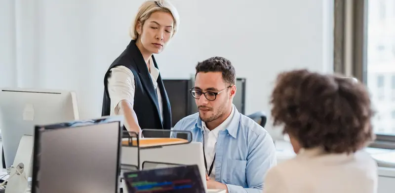 Office team working at desktop computers and laptops in a bright office
