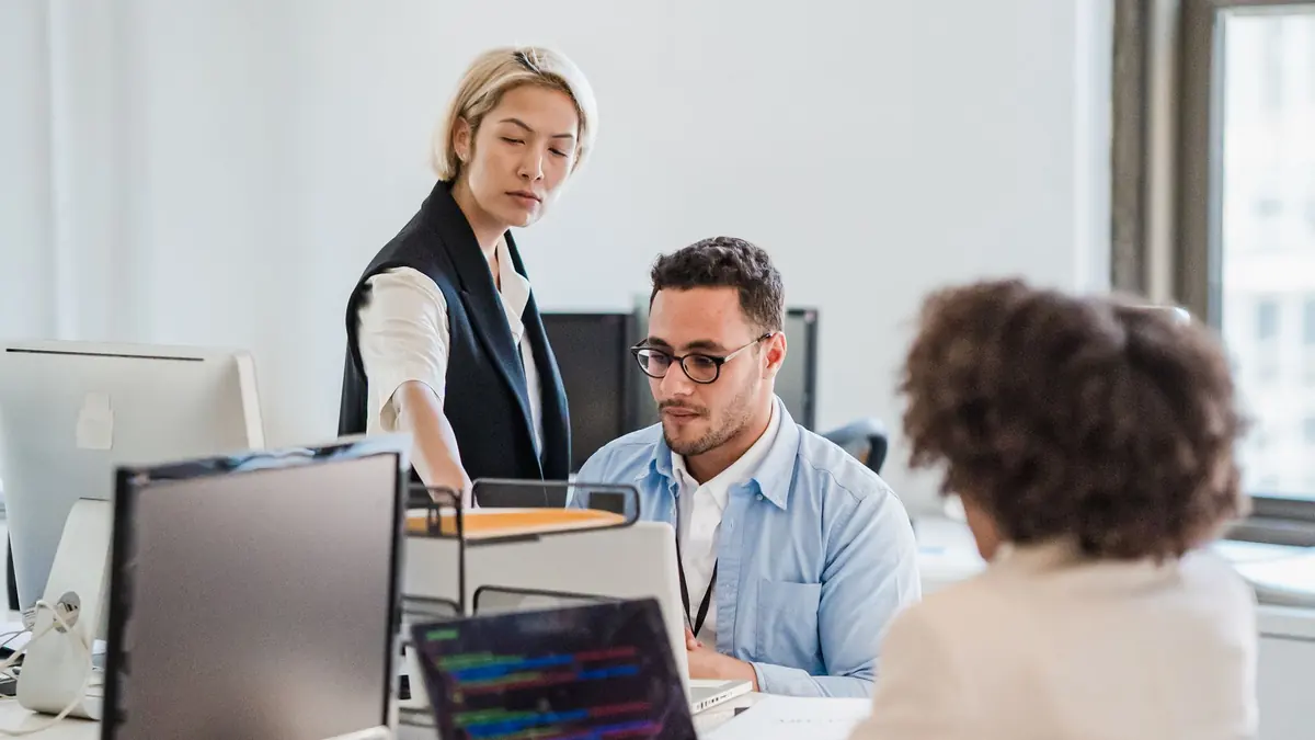 Office team working at desktop computers and laptops in a bright office