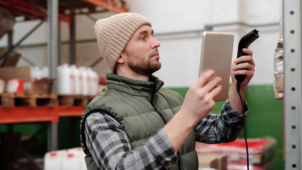 Warehouse worker scanning stock with a handheld scanner beside pallet racking